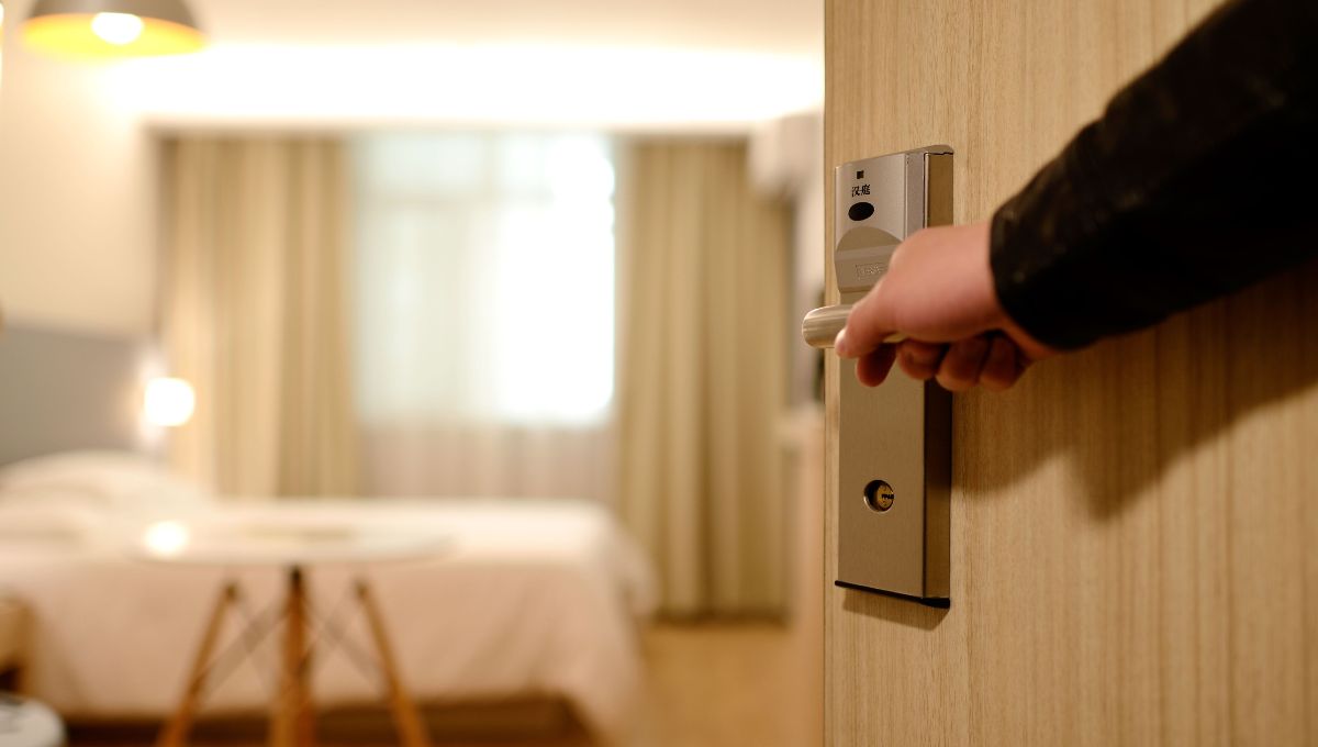 A hand on a door handle opening the door to a modern and clean hotel room