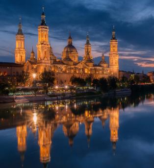 The Basílica de Nuestra Señora del Pilar lit up at night over the River Ebro