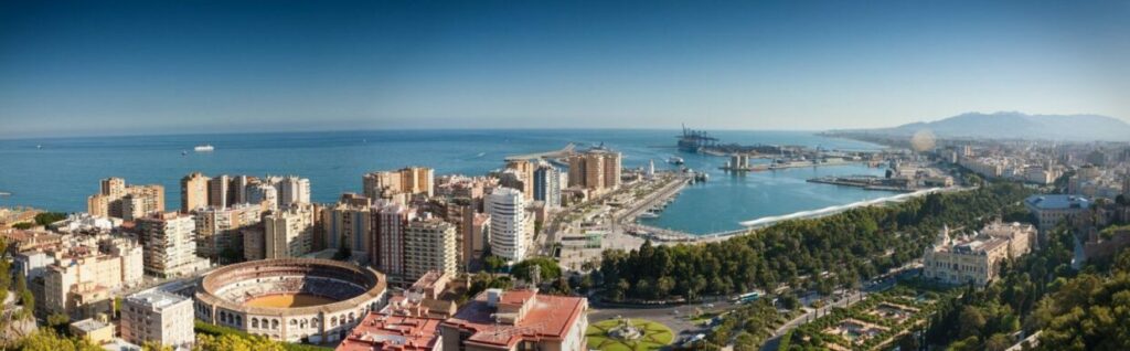 A panoramic photo of the Malaga skyline with the bullring in the forground and the ocean on the horizon.