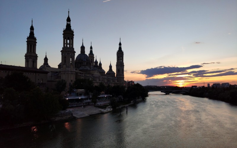 A silhouette of the Catedral-Basílica de Nuestra Señora del Pilar over the river Ebro at sunset in Zaragoza, Spain.