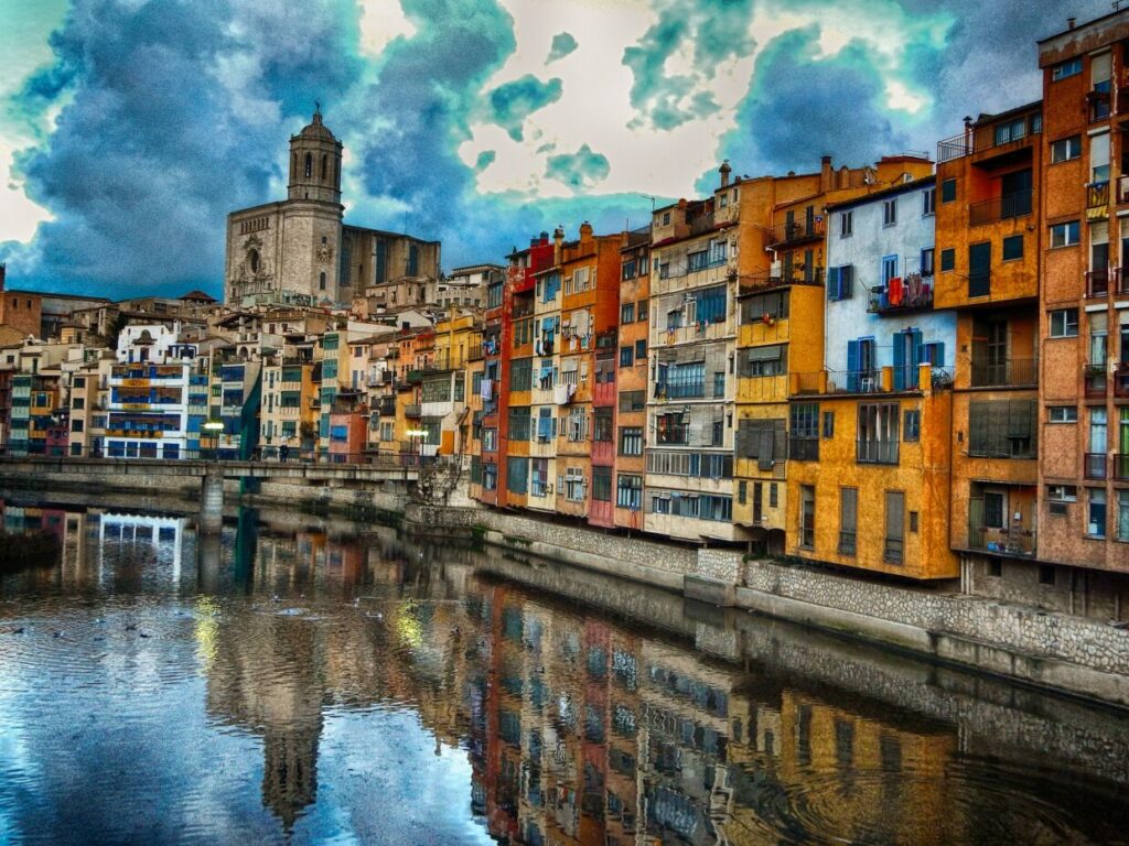 Colourful houses reflected in Onyar River with the cathedral tower in the background