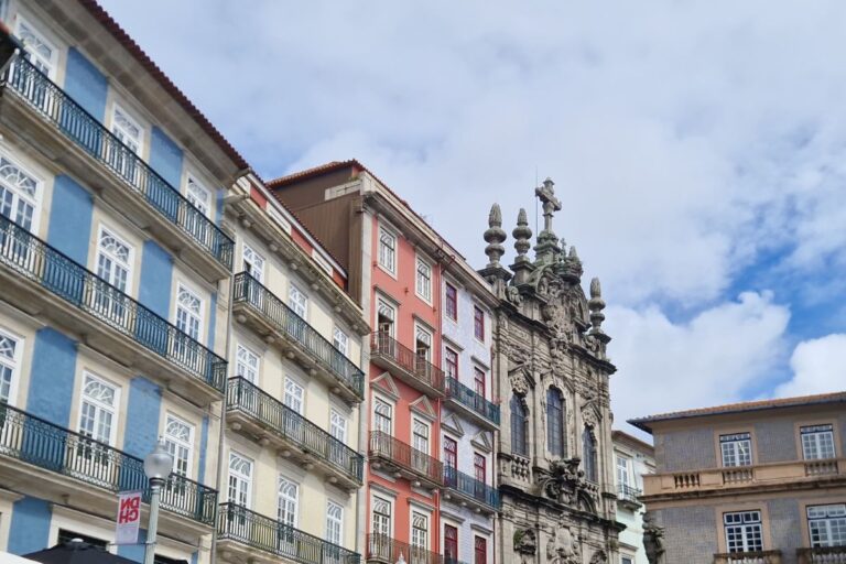 Colorful buildings and ornate architecture under a cloudy sky in Porto, showcasing the city's historic charm and vibrant facades.